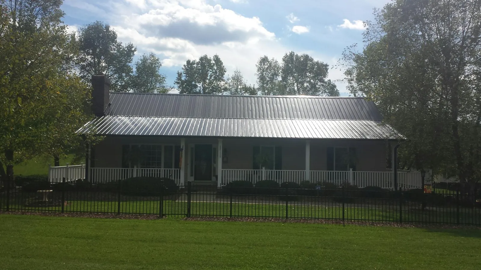 Gray metal roof on a brick ranch with a full width front porch — Gutter Guard Installation work by our crew in Trumbull